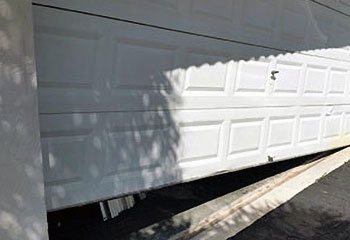 Damaged sectional garage door panel with visible denting needing repair in Carpentersville